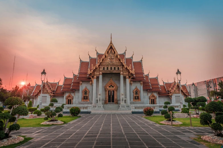 a large building sitting on top of a lush green field, a marble sculpture, pexels contest winner, thai temple, pink marble building, front symetrical, in the evening