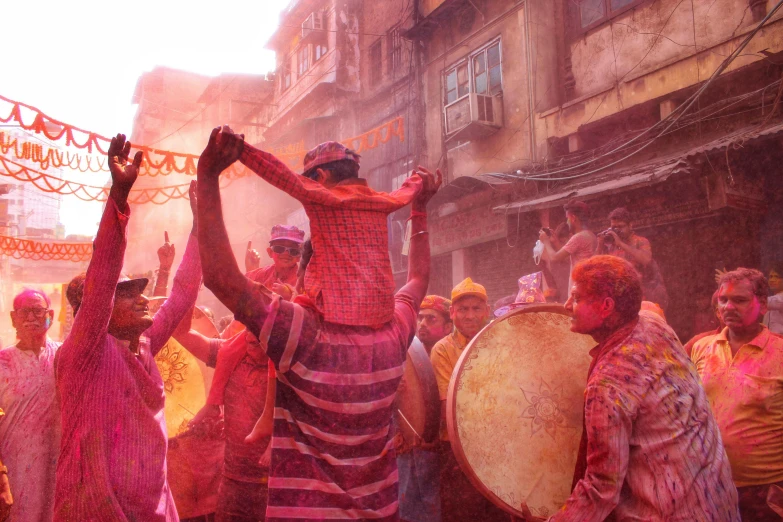 a group of people that are standing in the street, a colorized photo, pexels contest winner, bengal school of art, color pigments spread out in air, pink and orange colors, tribal red atmosphere, a still of a happy