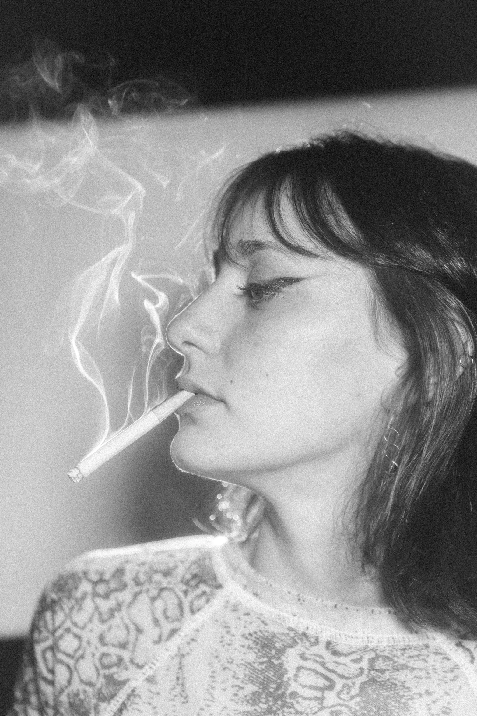 a black and white photo of a woman smoking a cigarette, inspired by Leila Faithfull, fluxus, messy bangs, pastel', ffffound, lights