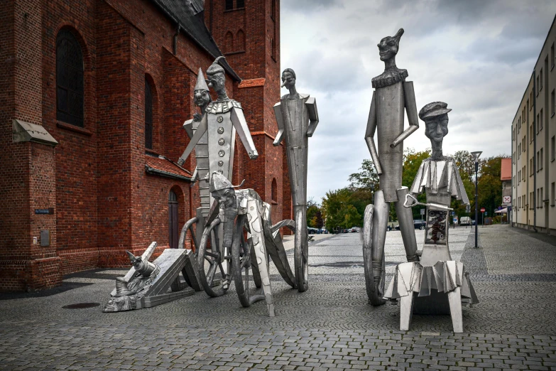 a couple of metal statues standing next to each other, inspired by Per Krohg, pexels contest winner, shining armour made of steel, people watching around, van allsburg, asymmetrical spires