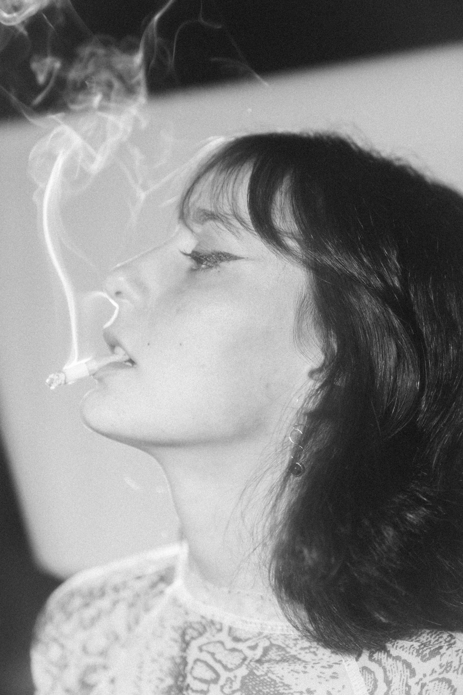 a black and white photo of a woman smoking a cigarette, by Grethe Jürgens, straight bangs, personification of marijuana, light haze, pastel'