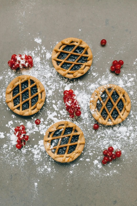 a group of pies sitting on top of a table covered in powdered sugar, a picture, by Julia Pishtar, pexels, berries inside structure, diecut, navy, 35 mm product photo”