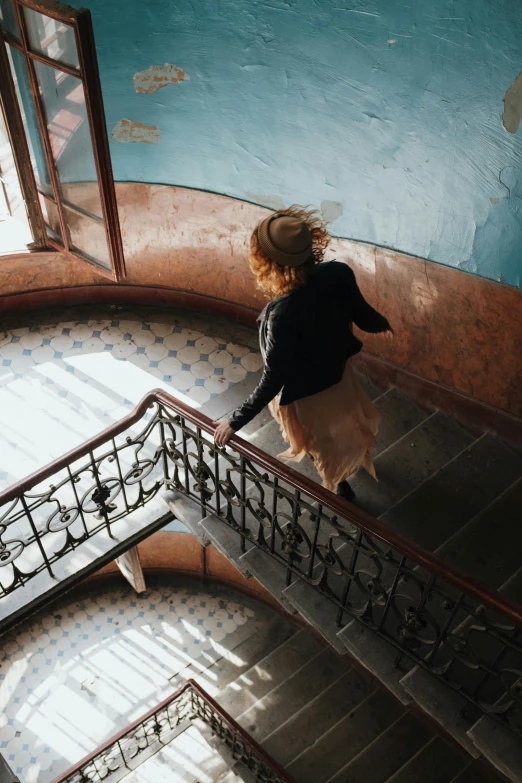 a woman walking up a set of stairs, inspired by Elsa Bleda, pexels contest winner, art nouveau, high view, half turned around, student, whirling