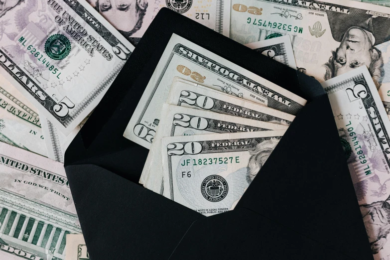 a black envelope sitting on top of a pile of money, listing image, zoomed in shots, thumbnail, stacked image