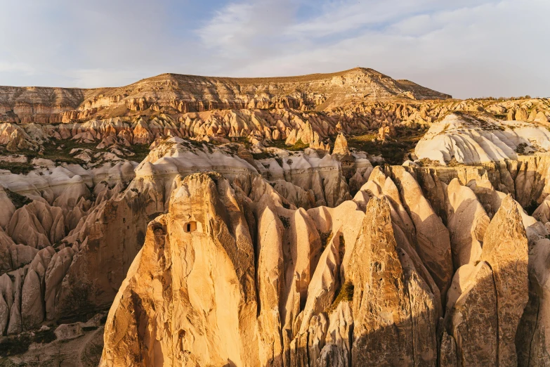 a large rock formation in the middle of a desert, pexels contest winner, art nouveau, cliff side at dusk, white travertine terraces, asymmetrical spires, birdseye view