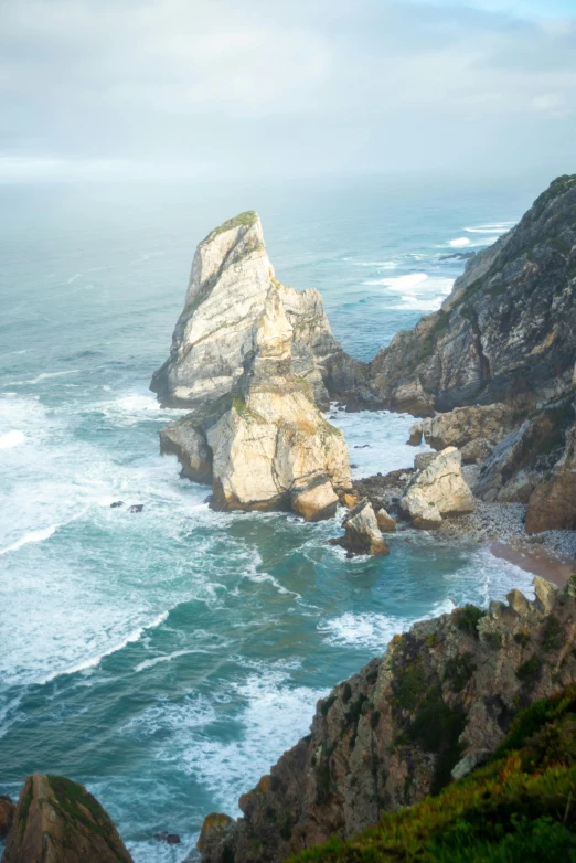 a large body of water sitting on top of a lush green hillside, an album cover, pexels contest winner, nazare (portugal), tall big rocks, square, winter