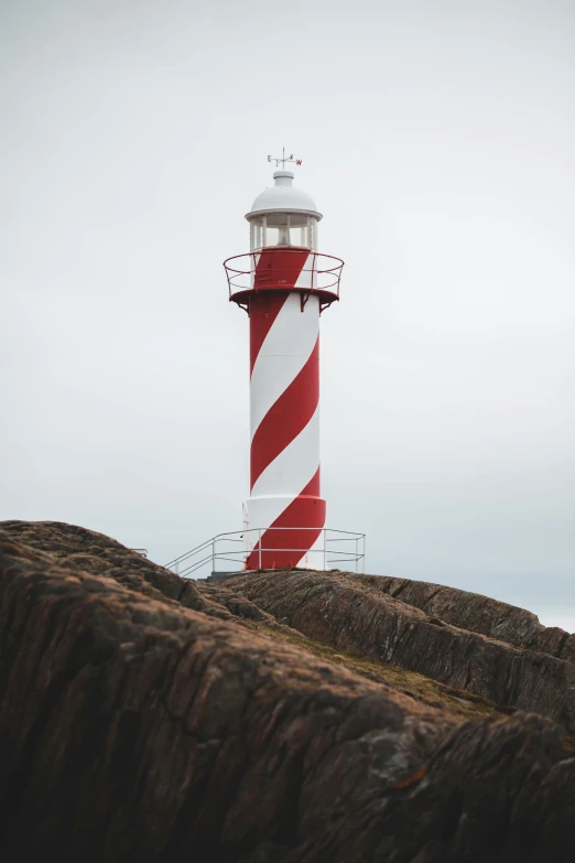 a red and white lighthouse sitting on top of a cliff, profile image, overcast lighting, red and white stripes, lights