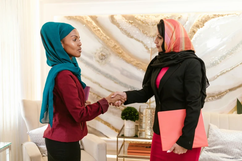 two women shaking hands in a living room, inspired by Maryam Hashemi, pexels contest winner, hurufiyya, wearing a head scarf, standing in the oval office, pink and teal, olivia pope