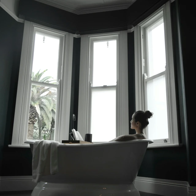 a woman sitting in a bathtub looking out a window, inspired by Sydney Prior Hall, unsplash, victorian room, wellington, low quality photo, multiple stories