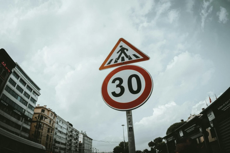 a close up of a street sign with buildings in the background, a picture, unsplash, 30 years old, traffic signs, 3 5 °, speed