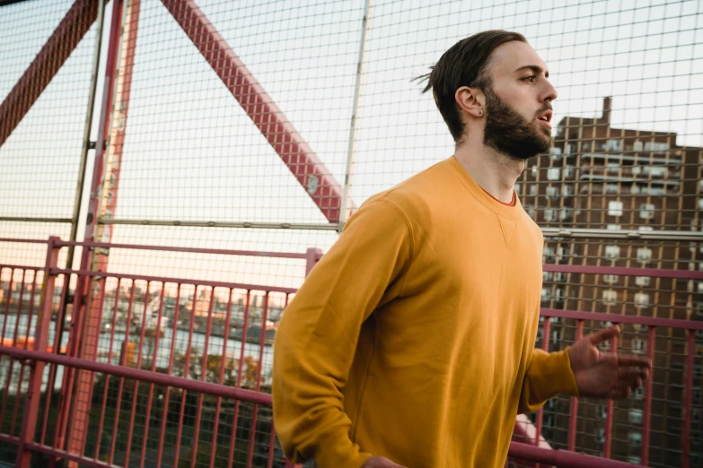 a man standing on a bridge talking on a cell phone, a portrait, pexels contest winner, happening, wearing a yellow hoodie, people running, bearded and built, youtube thumbnail