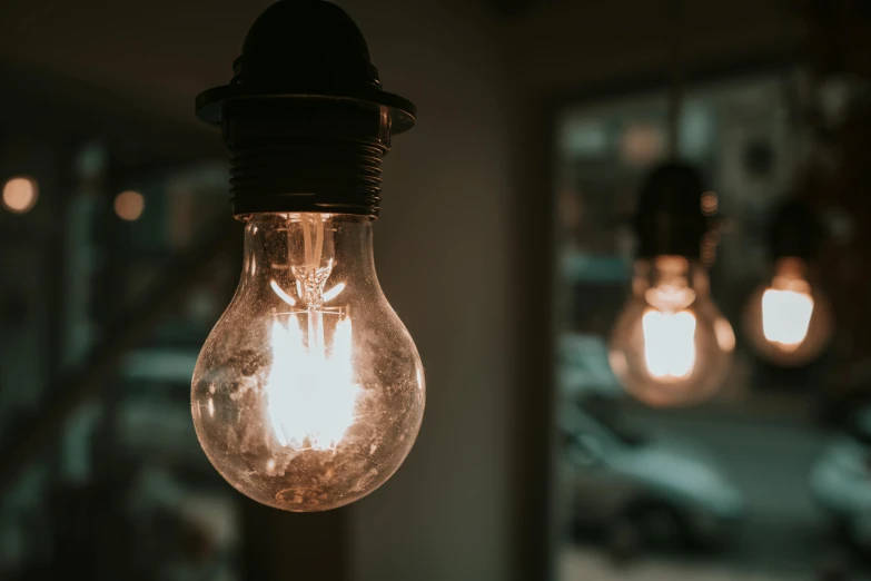 a close up of a light bulb hanging from a ceiling, pexels, lights are on in the windows, paul barson, warm dim light, light source from the left