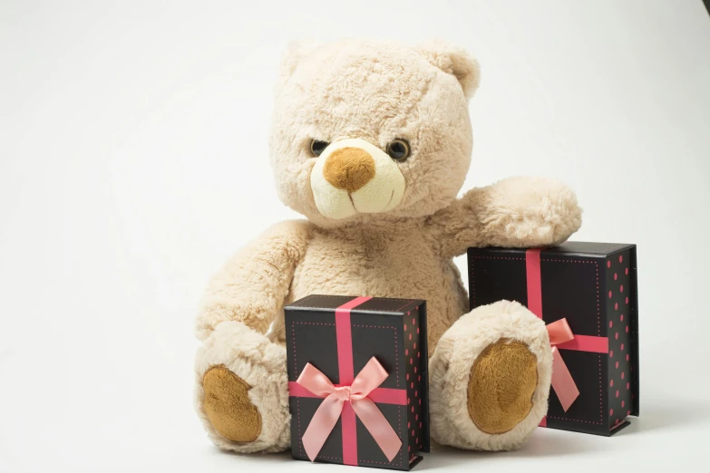 a teddy bear sitting next to two gift boxes, pexels, romanticism, black, tan, pink, toddler