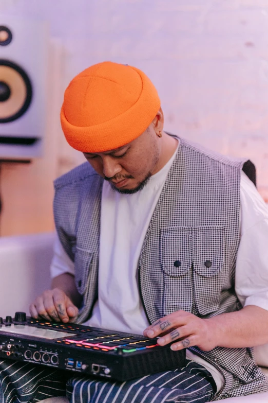 a man in an orange turban playing a keyboard, an album cover, inspired by Pablo Carpio, unsplash, lyco art, playing techno house music, asian male, berets, sitting down
