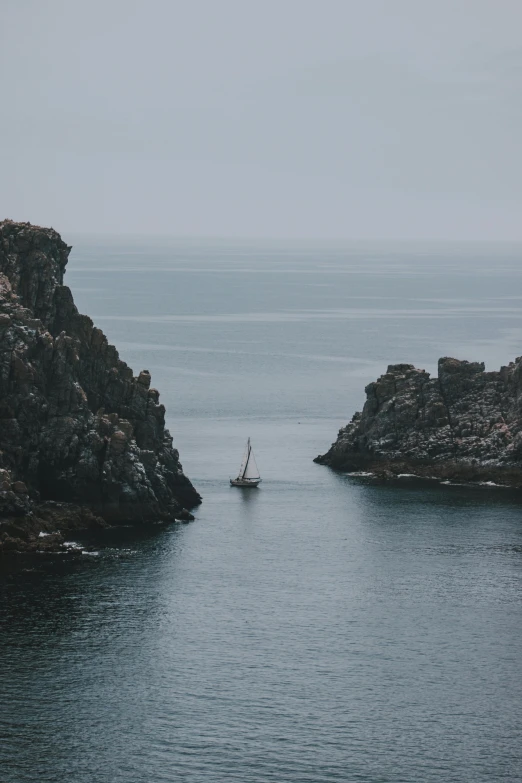 a boat in the middle of a body of water, by Jesper Knudsen, pexels contest winner, rocky cliffs, devils horns, low quality photo, grey