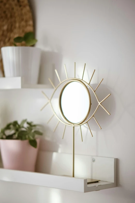 a mirror sitting on top of a shelf next to a potted plant, inspired by karlkka, new sculpture, glowing eye, medium close - up, gold, home display