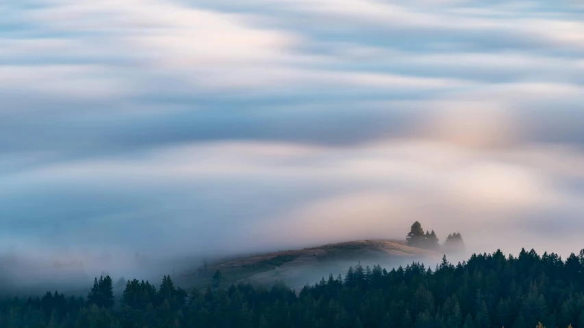 a mountain covered in a thick layer of clouds, a picture, by Doug Ohlson, unsplash contest winner, romanticism, hill with trees, long exposure, late summer evening, grey