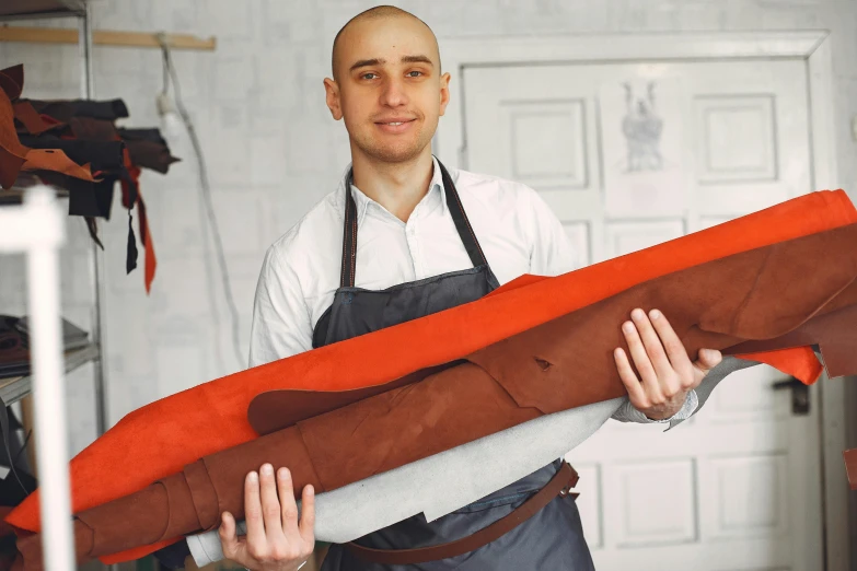 a man holding a large piece of fabric in his hands, pexels contest winner, arbeitsrat für kunst, leather apron, anna nikonova aka newmilky, terracotta, very long arms