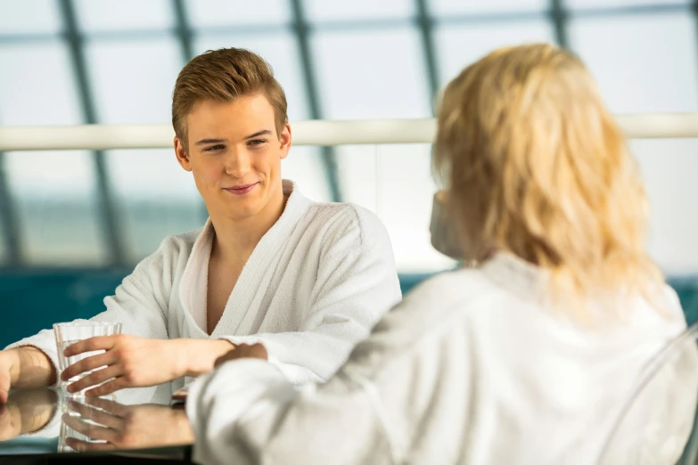 a woman in a white robe is shaking hands with a man in a white robe, a portrait, by Julian Allen, shutterstock, teenage boy, spa, aussie baristas, looking from shoulder