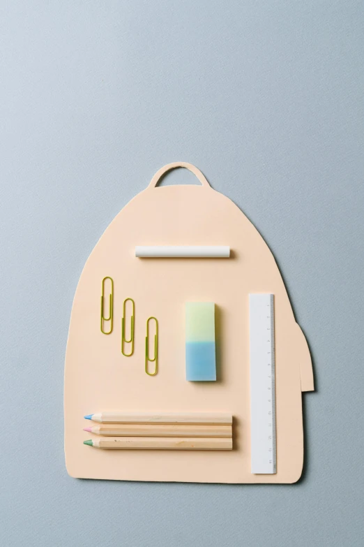 a backpack with school supplies on top of it, by Jang Seung-eop, shaped picture, matte surface, in shades of peach, detail shot