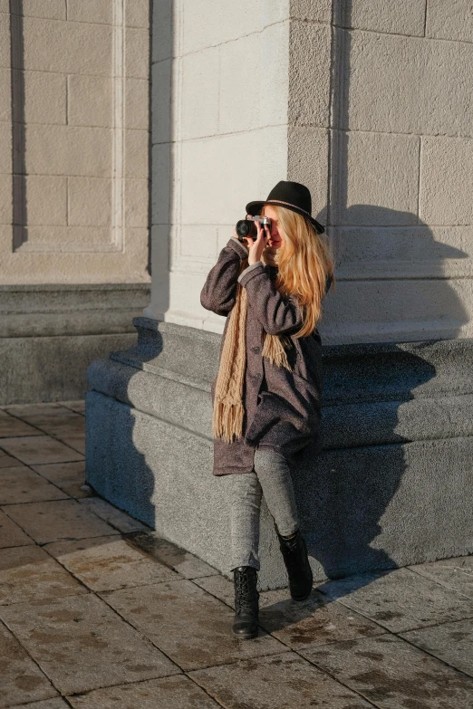 a woman taking a picture of herself in front of a building, pexels contest winner, visual art, action shot girl in parka, long shadow, a blond, taken in the late 2010s