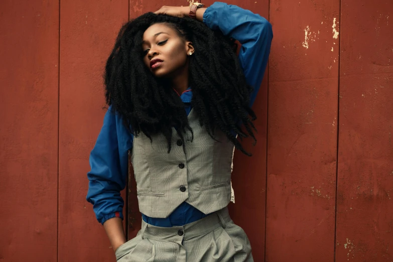 a woman with long hair leaning against a red wall, by Carey Morris, trending on pexels, wearing a waistcoat, willow smith young, wearing wool suit, girl wearing uniform