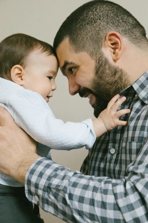 a man holding a baby in his arms, pexels, bushy beard, looking at each other mindlessly, full color still, panels