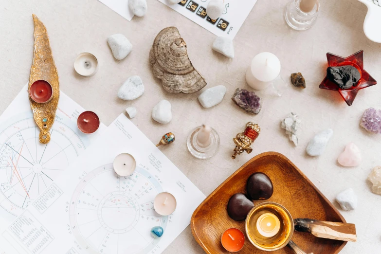 a wooden bowl sitting on top of a table, a still life, by Julia Pishtar, trending on pexels, floating symbols and crystals, character sheets on table, pins of light, shells