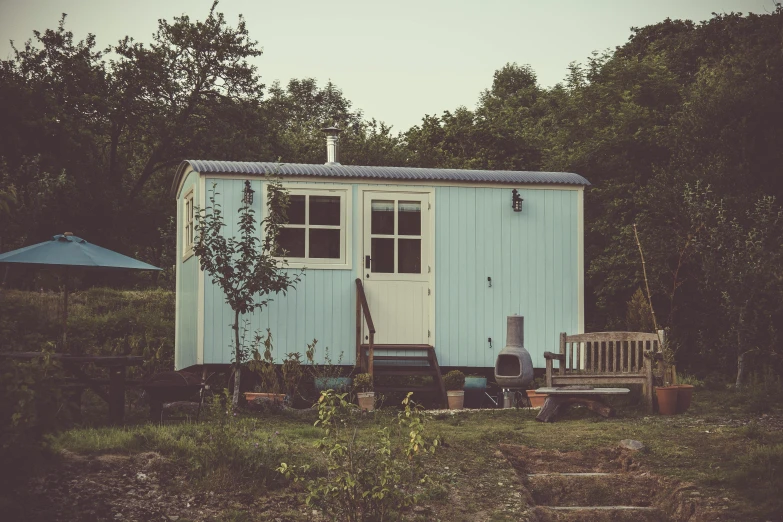 a blue house sitting on top of a lush green field, a colorized photo, by Elsa Bleda, unsplash, caravan, inside a shed, hygge, built on a small