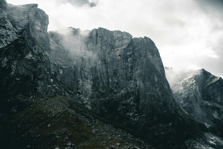 a person standing on top of a mountain under a cloudy sky, pexels contest winner, minimalism, extremely detailed rocky crag, grey mist, seen from a distance, ominous dramatic wide angle