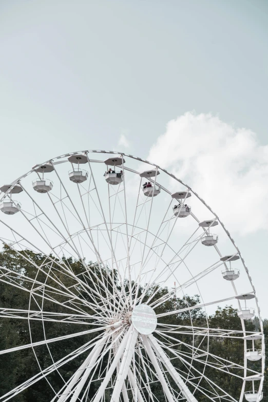 a large ferris wheel sitting in the middle of a park, unsplash contest winner, aestheticism, white and pale blue, round clouds, large crown, minimalistic aesthetics