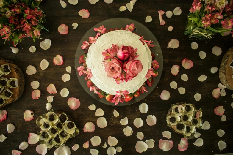 a table topped with a white cake covered in pink flowers, inspired by Annabel Kidston, pexels, renaissance, ariel view, lotus petals, 3/4 front view, rustic