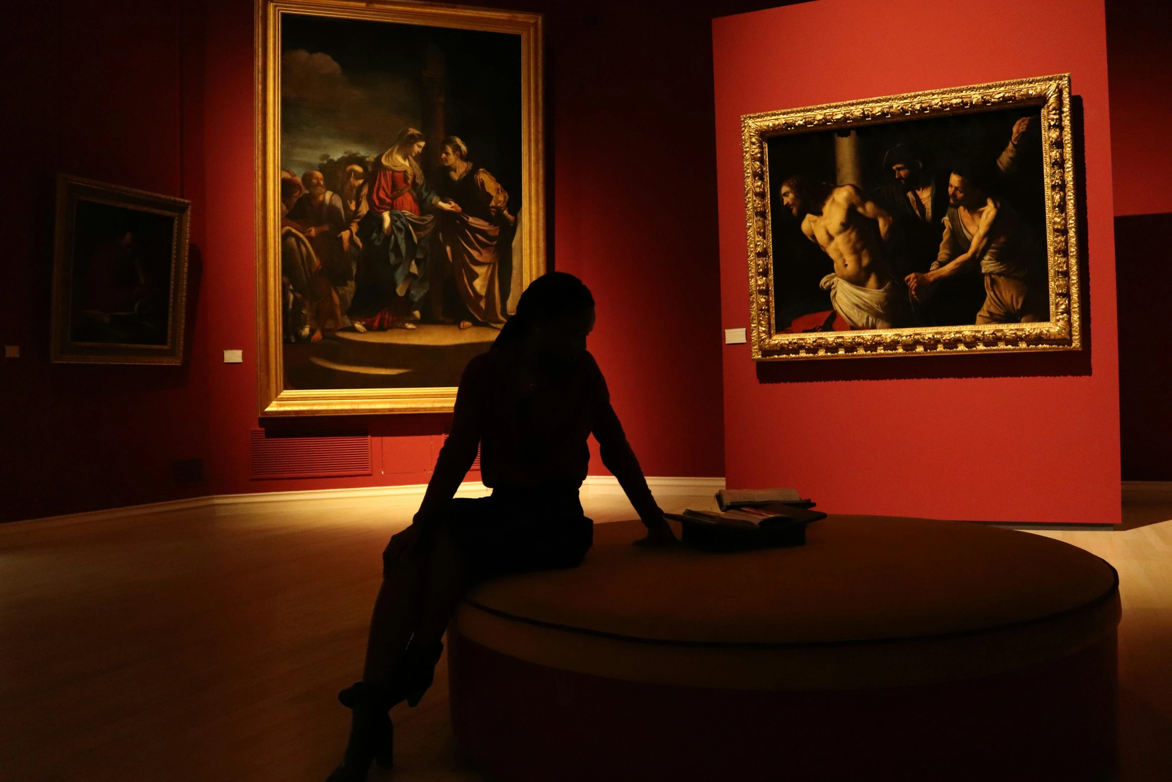 a woman sitting on a bench in a museum, inspired by Caravaggio, pexels contest winner, gallery lighting, titian], person in foreground, simone graci