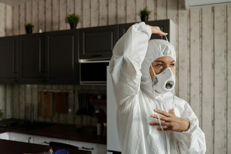 a woman wearing a protective suit and a gas mask, pexels contest winner, in a kitchen, wearing white silk robe, as she looks up at the ceiling, wearing a tracksuit