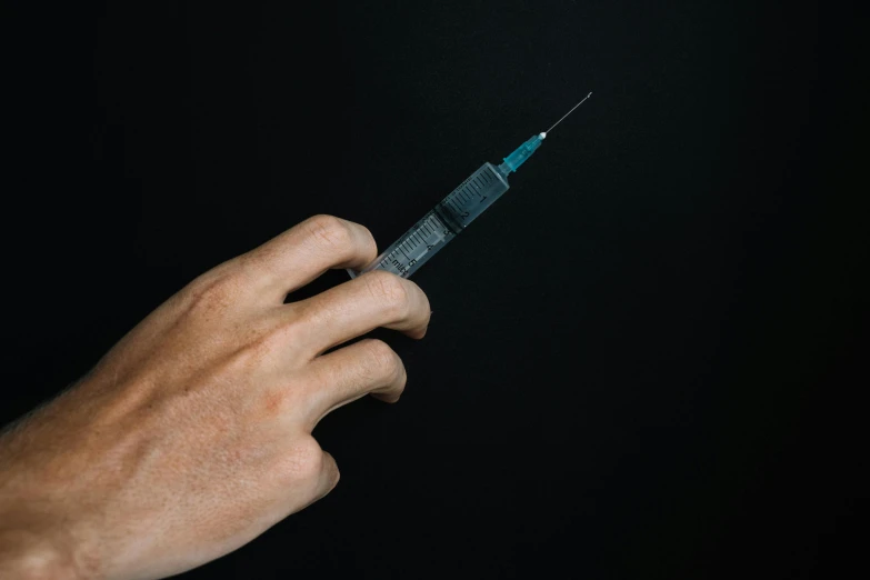 a person holding a syet in their hand, by Adam Marczyński, unsplash, hurufiyya, holding syringe, black and teal paper, microchips, steroid use