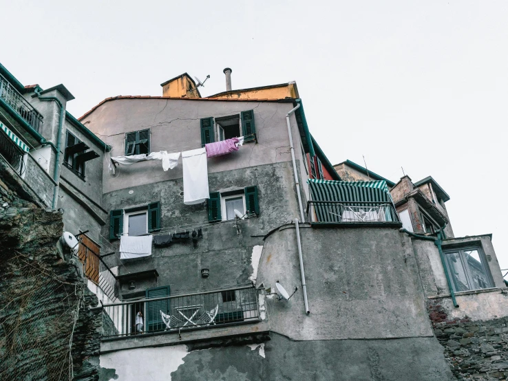 a building with clothes hanging out to dry, by Daniel Lieske, pexels contest winner, renaissance, cinq terre, photo of poor condition, grey, videogame still