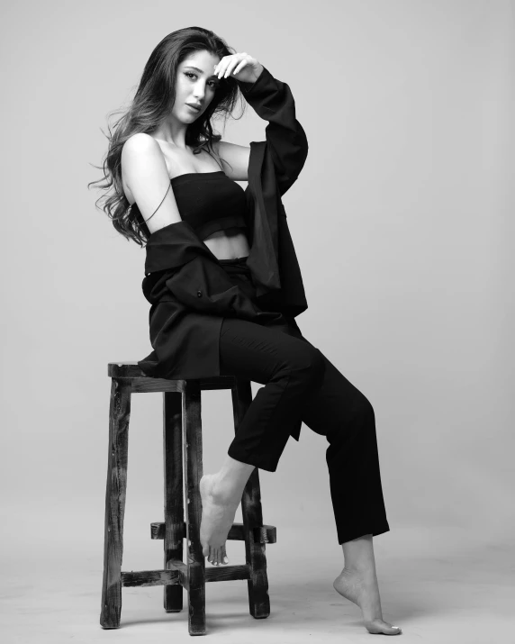 a woman sitting on top of a wooden chair, a black and white photo, trending on cgsociety, fashion shoot 8k, black clothes, various poses shooting photos, “megan fox