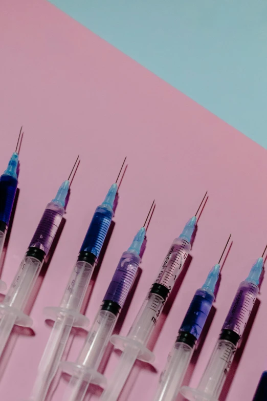 a row of sylls sitting on top of a pink surface, trending on pexels, panfuturism, holding a syringe, thin blue arteries, instagram post, vibrant vials