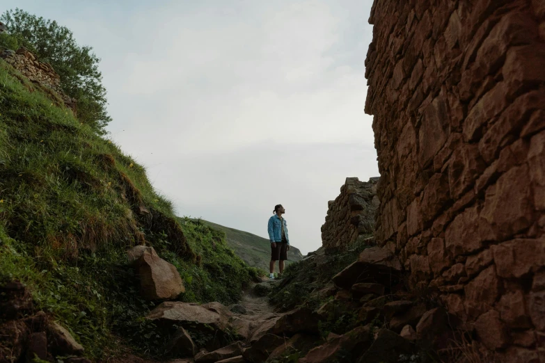 a man standing on top of a rocky hill, by Attila Meszlenyi, unsplash contest winner, standing in an alleyway, west slav features, profile picture 1024px, at the stone ruins