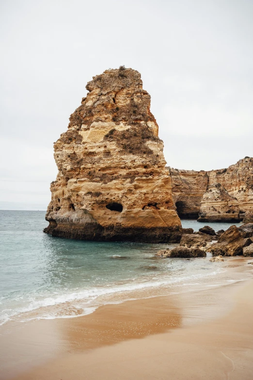 a couple of rocks sitting on top of a sandy beach, grotto, buttresses, insanely precise, port