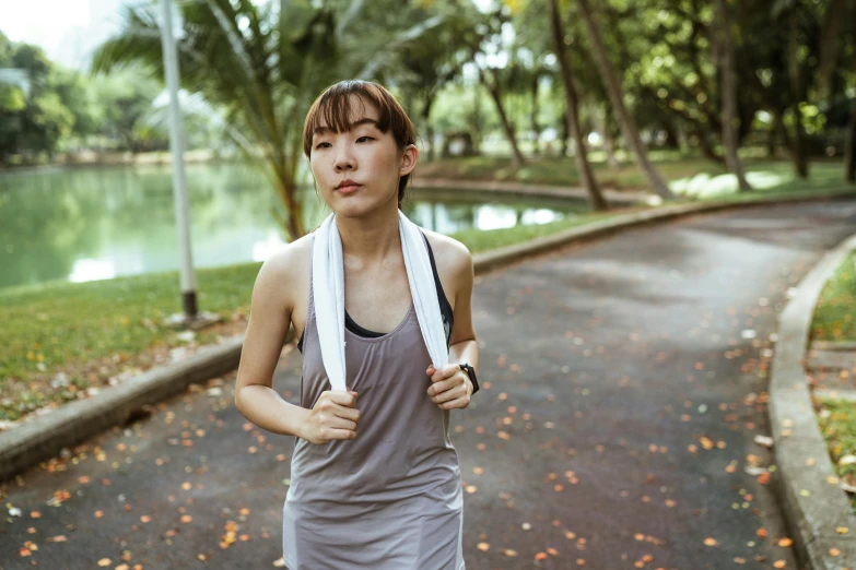 a woman running in a park with a towel around her neck, a portrait, inspired by Ruth Jên, pexels contest winner, happening, wearing : tanktop, malaysian, avatar image, blank