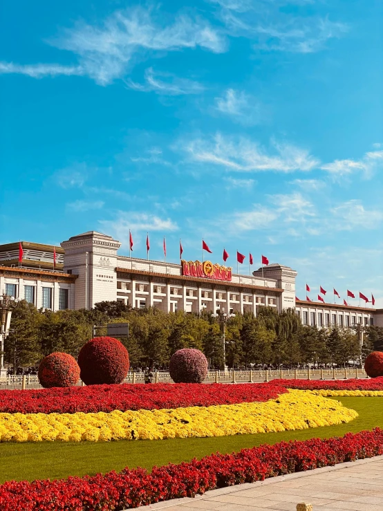 a large building with red and yellow flowers in front of it, inspired by Wang Zhongyu, pexels contest winner, socialist realism, a park, promo image, panoramic shot, tiananmen square