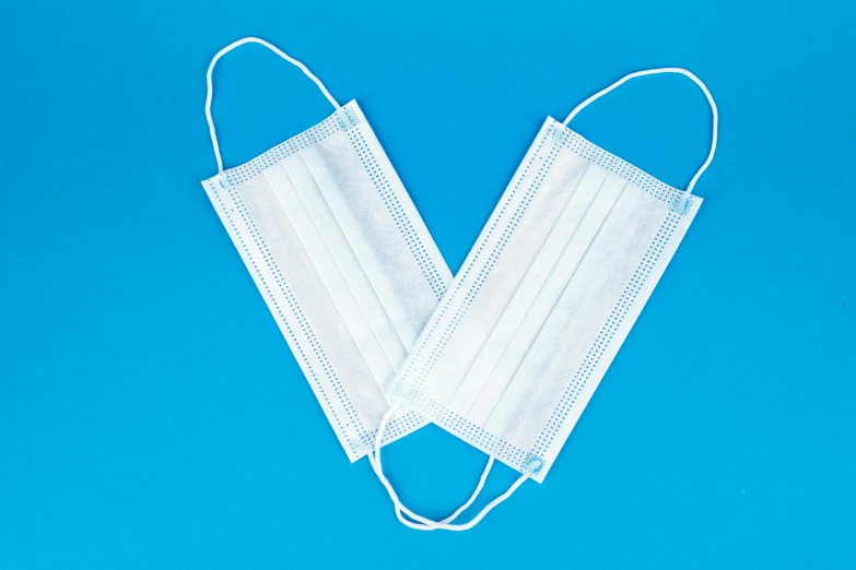 a pair of disposable face masks on a blue background, product image, bandoliers, unbeatable quality, white panels