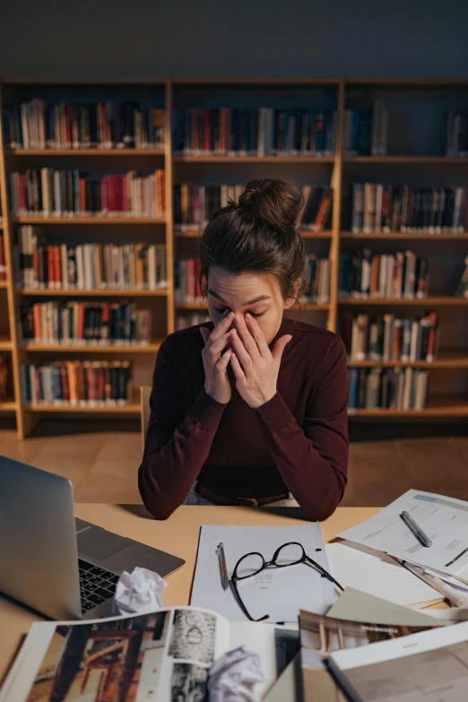 a woman sitting at a table in front of a laptop computer, unsplash contest winner, academic art, woman crying, in a library, disease, hungover