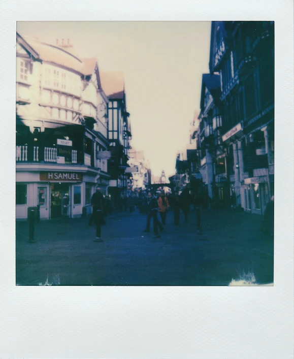 a group of people walking down a street next to tall buildings, a polaroid photo, by IAN SPRIGGS, unsplash, chesterfield, old shops, town square, outside the'school of magic '