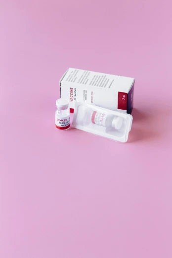 two vials sitting next to each other on a pink surface, by Rachel Reckitt, unsplash, red cross, still in package, hegre, detailed product image