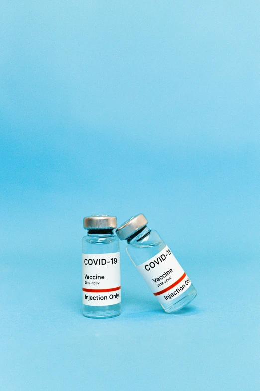 two vials of covidd vaccine on a blue background, a picture, by Gavin Hamilton, story, plain background, on ship, thumbnail