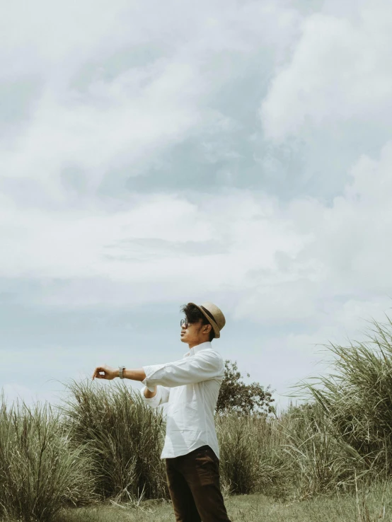 a man standing in a field flying a kite, unsplash, visual art, wearing a white button up shirt, indonesia, holding a pocket watch, profile image