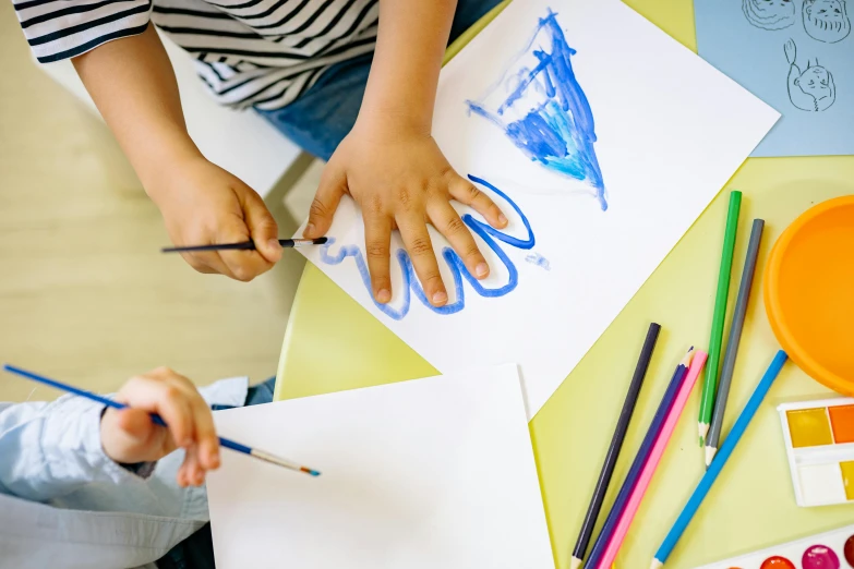 a couple of kids that are sitting at a table, a child's drawing, pexels contest winner, symmetrical hands, blue paint on top, diagonal strokes, trending art station