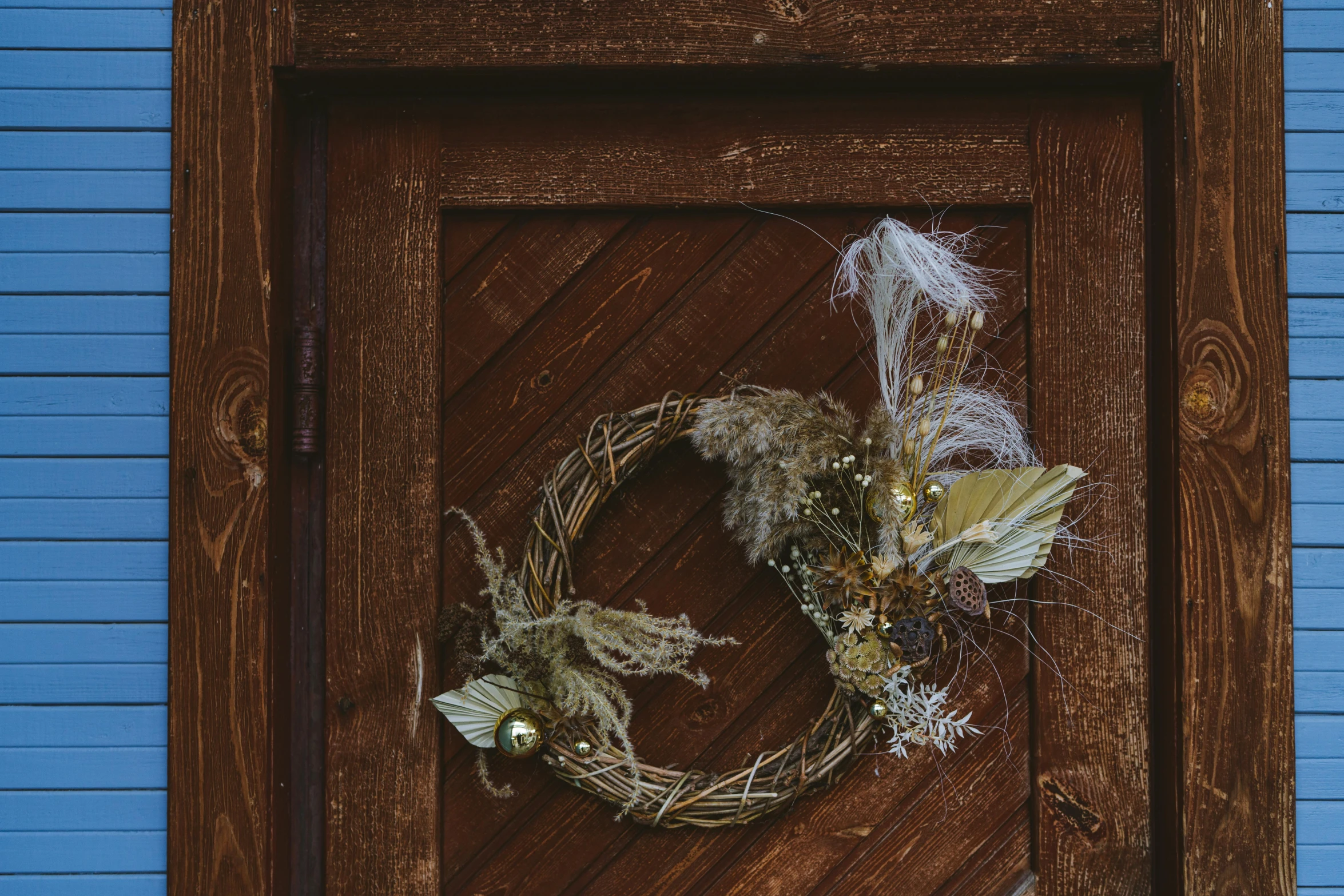 a close up of a door with a wreath on it, by Attila Meszlenyi, pexels contest winner, arts and crafts movement, dry grass, tawny frogmouth, handcrafted, golden accents